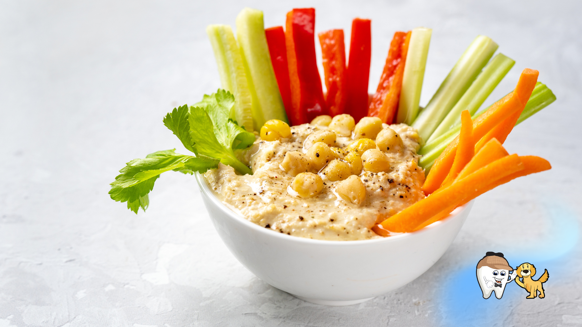 Veggie sticks with dip in a white bowl, arranged in a colorful fan of carrots, celery, and peppers
