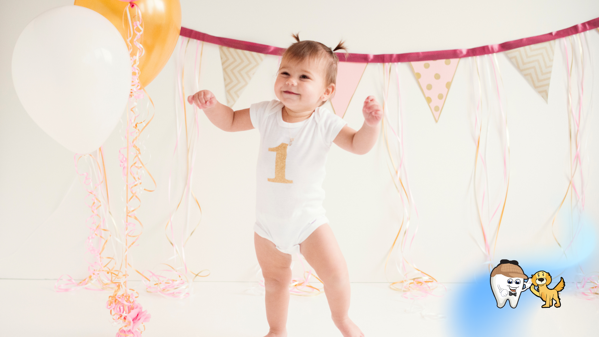 A baby girl is standing in front of balloons and flags.