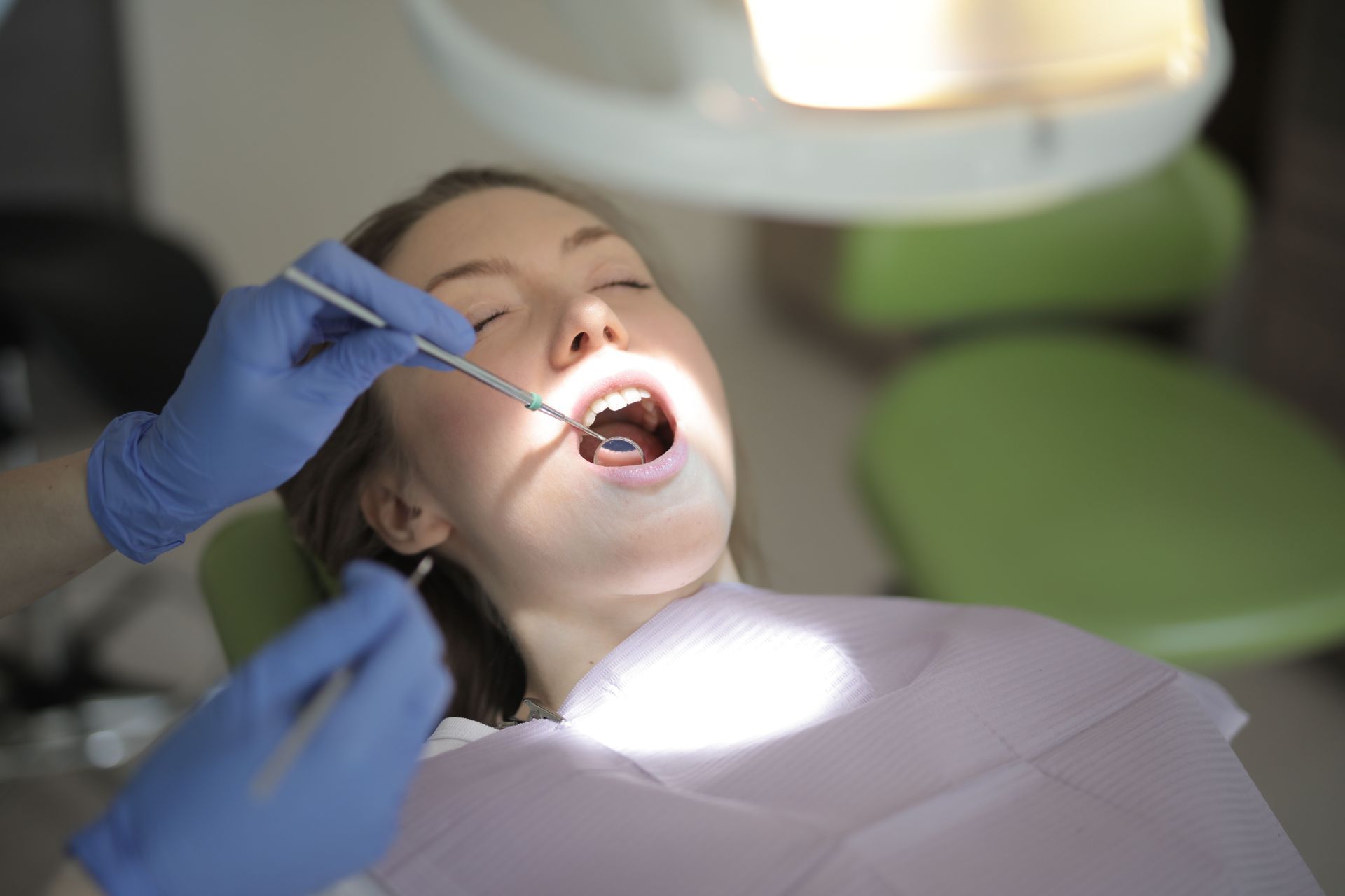 Dentist holding a dental model with teeth, roots, and an implant illustration