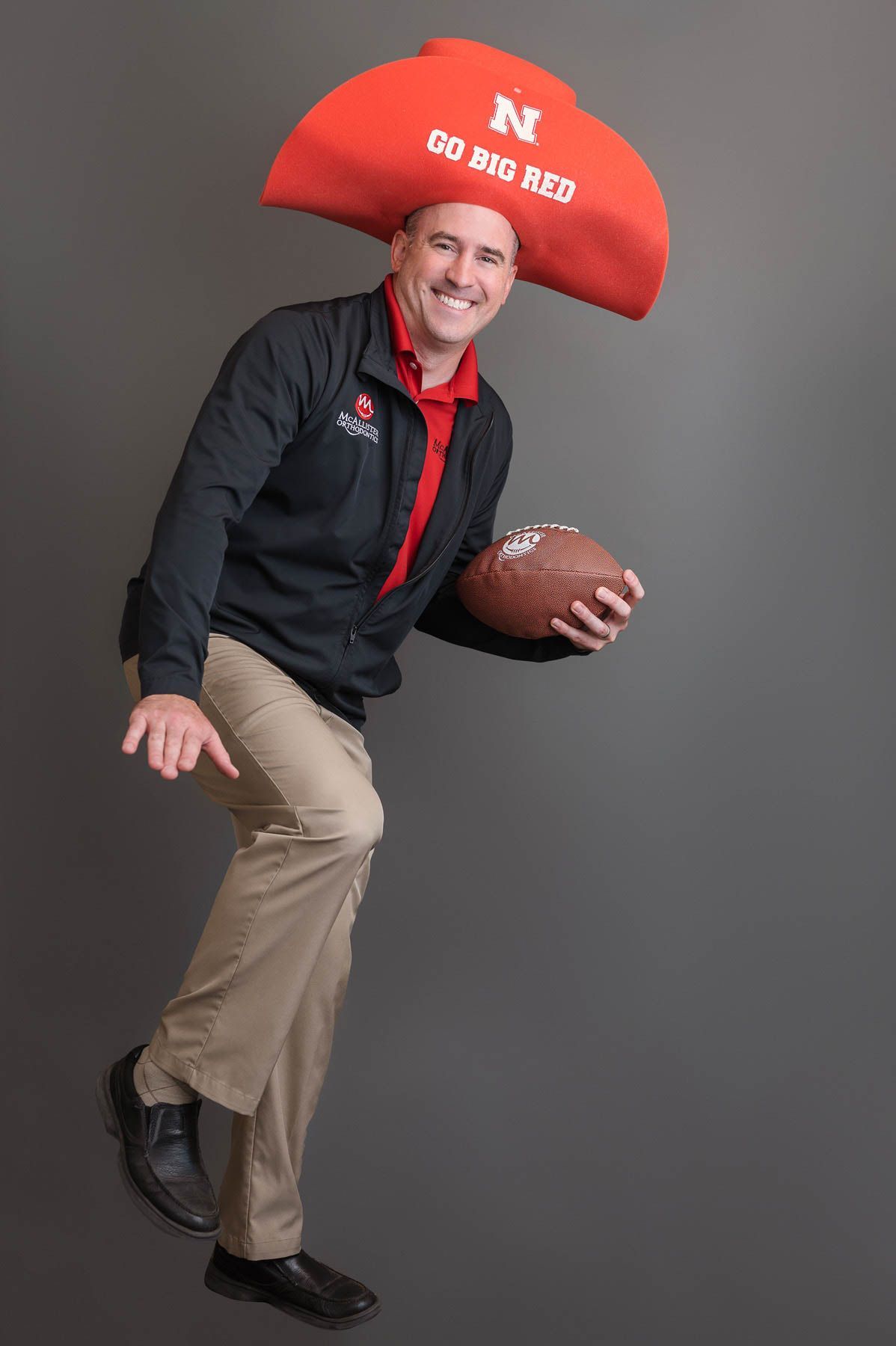 A man wearing a red cowboy hat is holding a football.