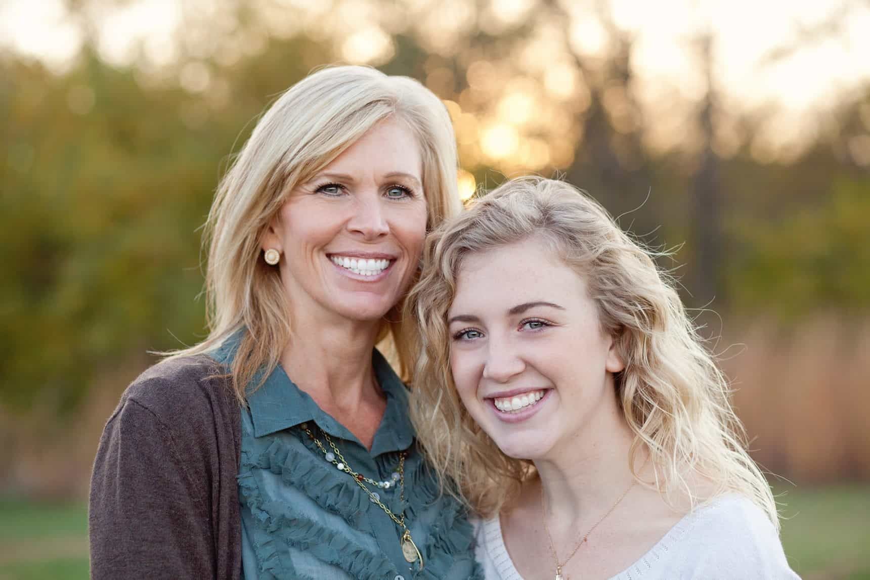 A mother and daughter are posing for a picture together and smiling.
