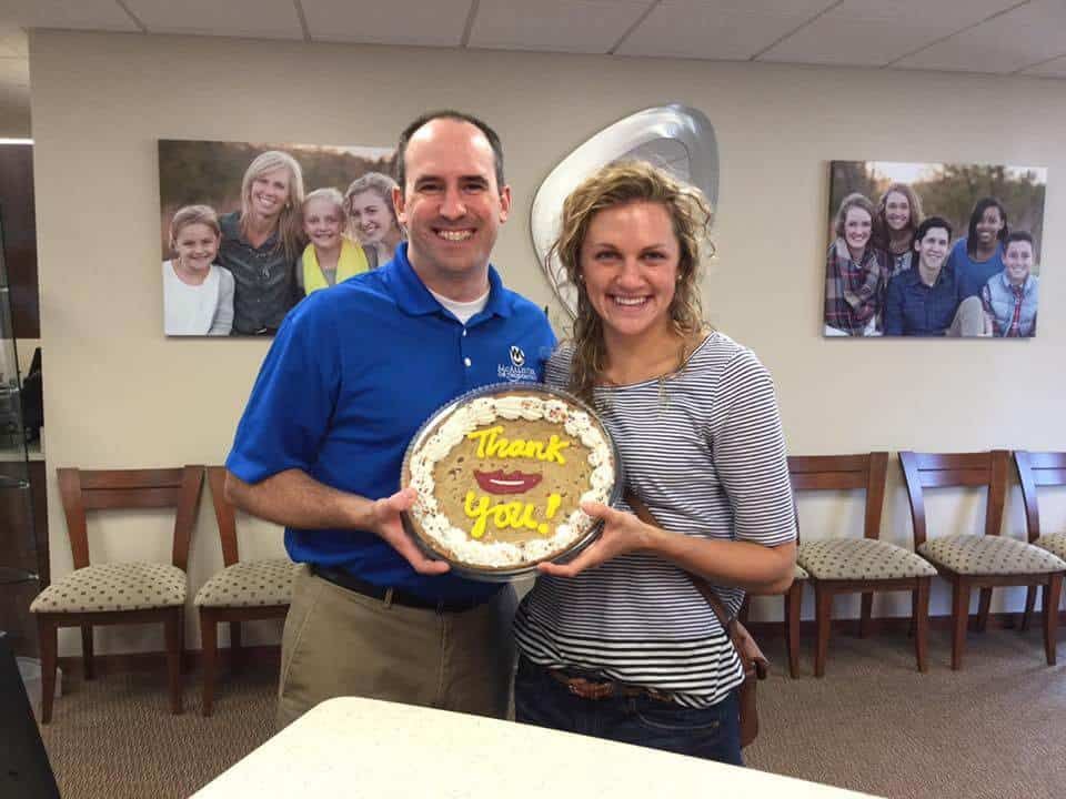 A man and a woman are holding a cake that says thank you