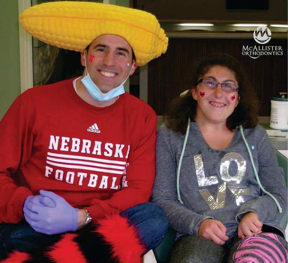 A man wearing a nebraska football shirt sits next to a girl