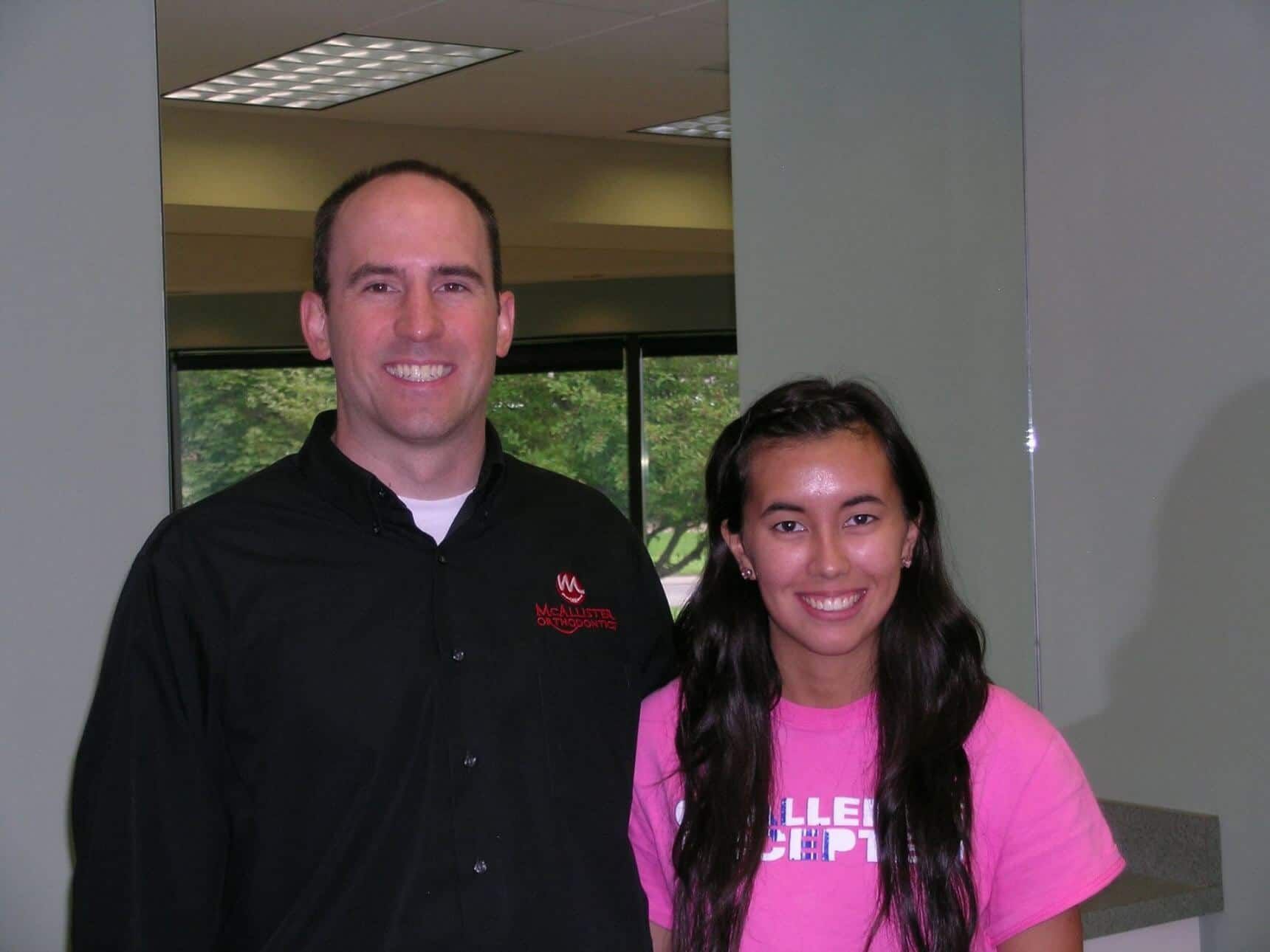 A man and a woman are posing for a picture and the woman is wearing a pink shirt.