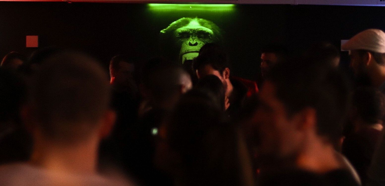 Un groupe de personnes se tient dans une pièce sombre avec un singe sur le mur.