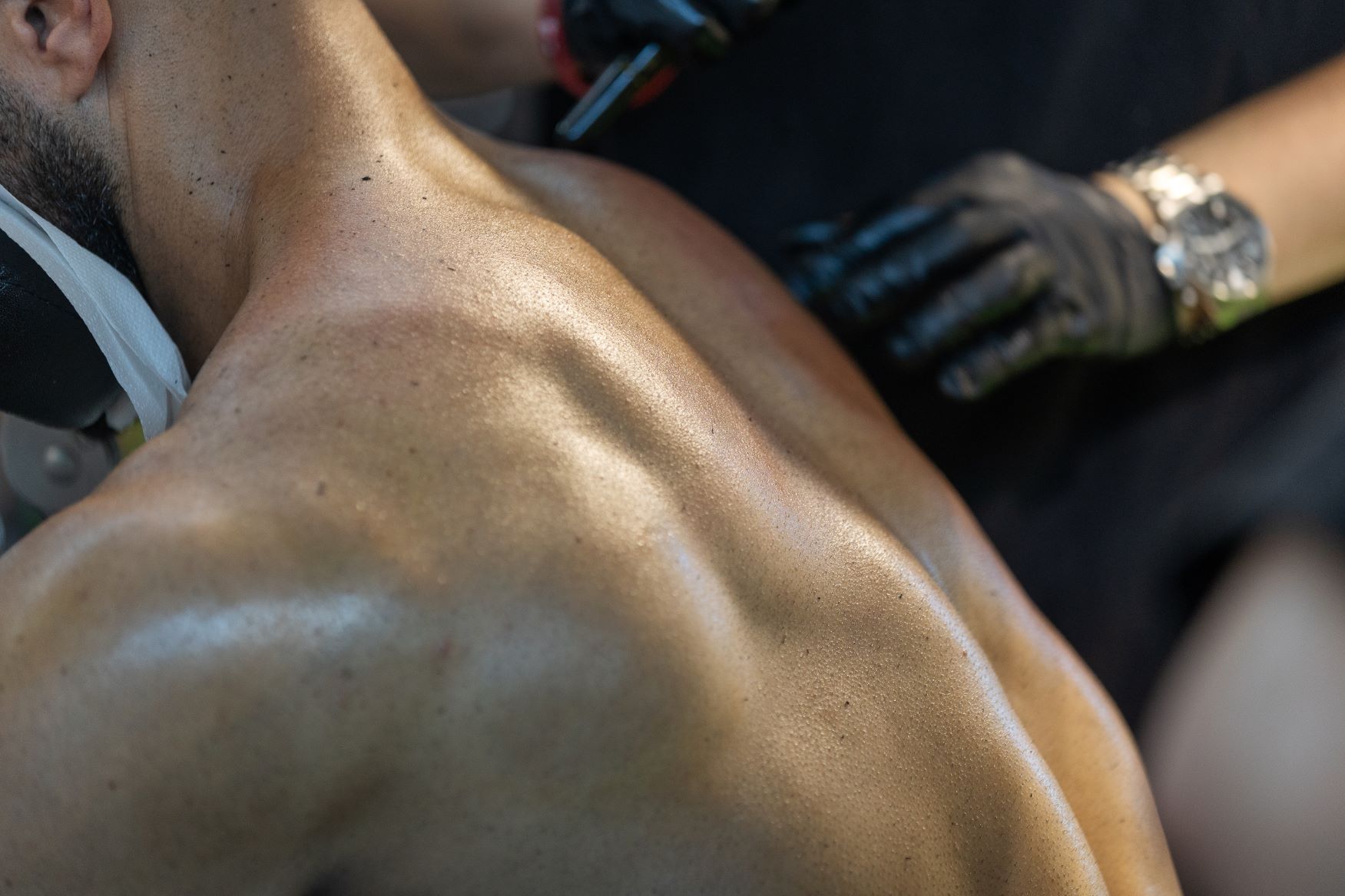 A close up of a man 's back with a woman standing behind him.