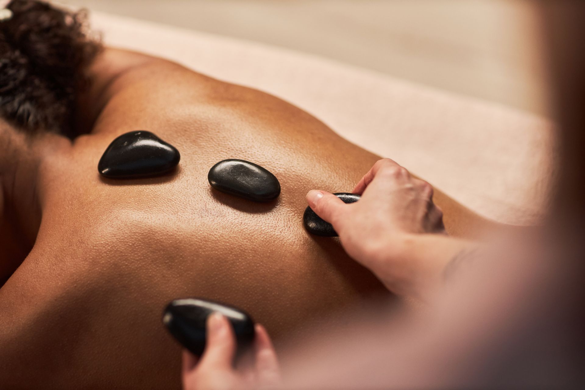 A woman is getting a hot stone massage on her back.
