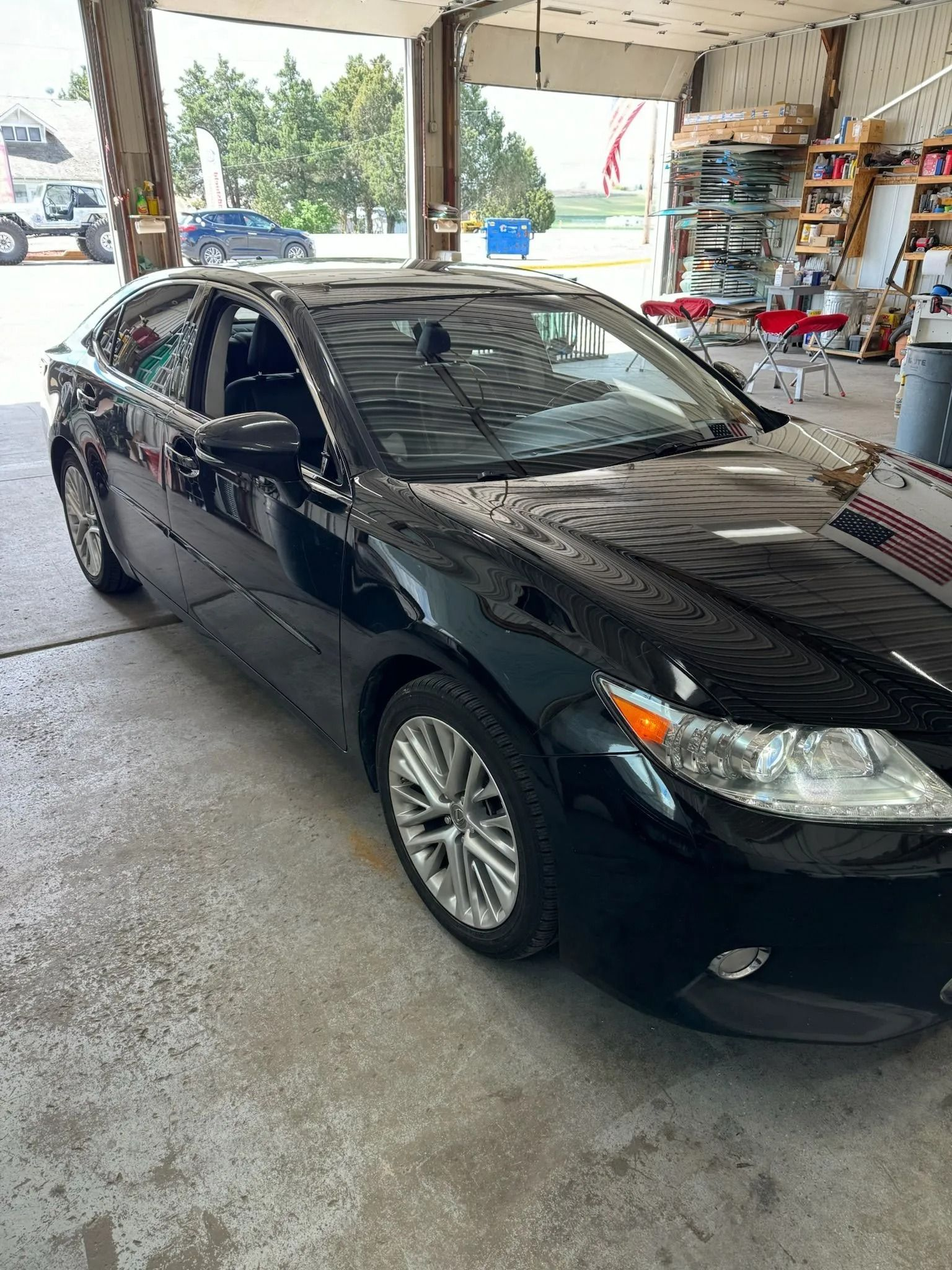 A black sedan parked inside a well-lit, open-bay automotive repair shop.