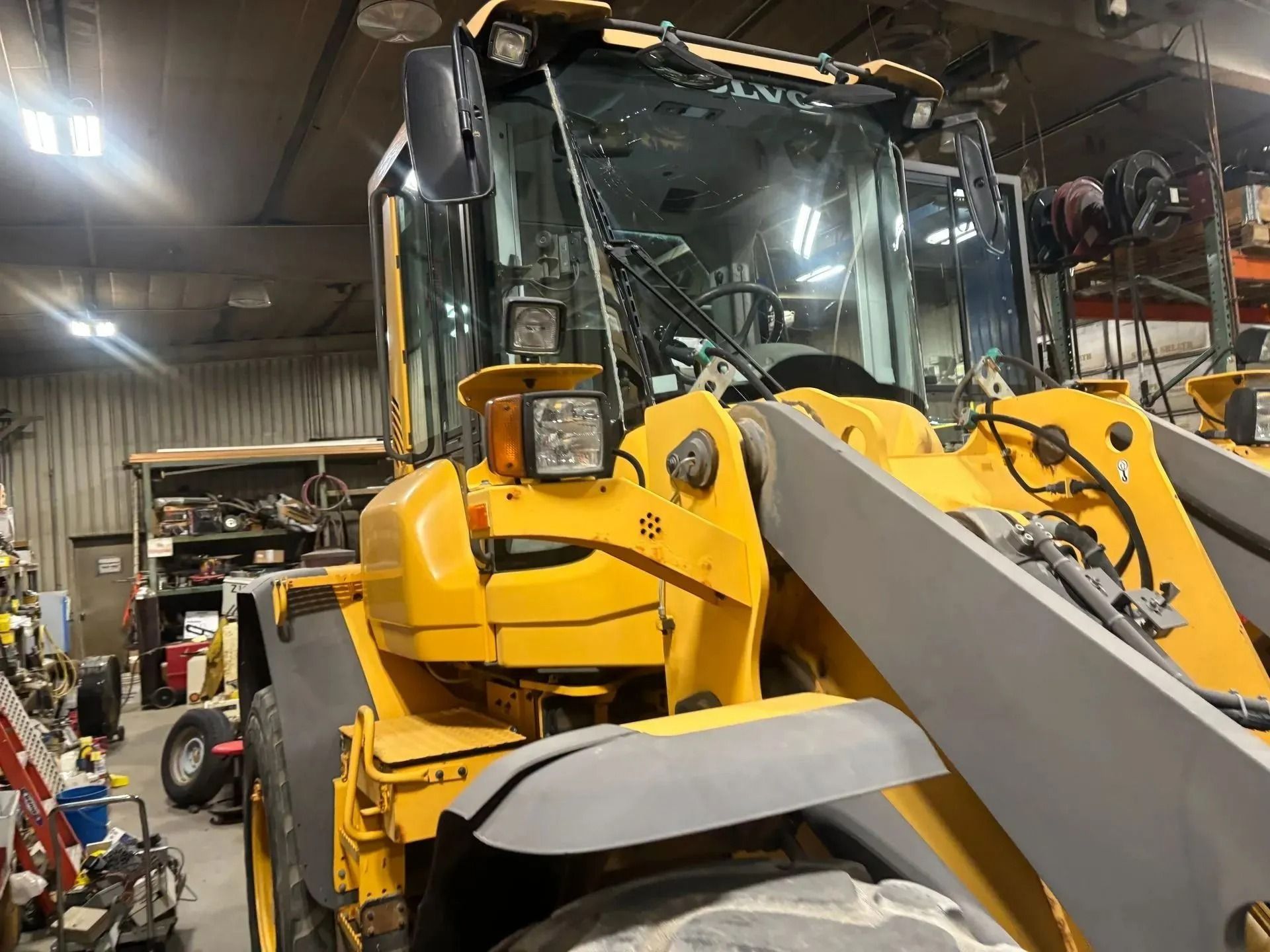 A close-up view of a yellow Volvo wheel loader parked inside a maintenance shop or garage.