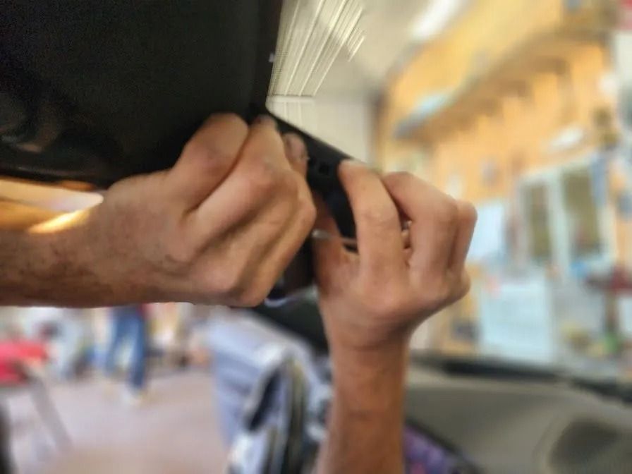 Close-up of hands adjusting the interior rearview mirror of a vehicle inside a garage.