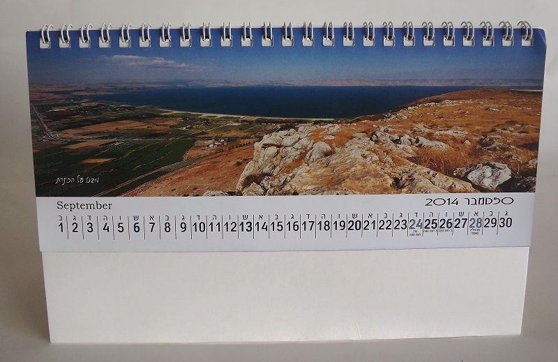 לוח שנה שולחני עומד קטן עם כריכת ספירלה. מציג פריסת חודש קלאסית בטבלה (ספטמבר 2014) על רקע לבן עם הדגשות בצבע כחול.