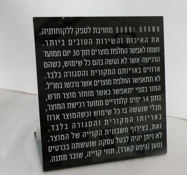שלט פרספקס שחור מעוצב לדלפק המציג את מדיניות ההחלפות ושירות הלקוחות של מותג BOBBI BROWN.