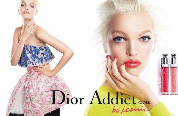 גלוית פרסום צבעונית לבשמי ומוצרי האיפור של Dior Addict לצד דוגמנית ברקע.