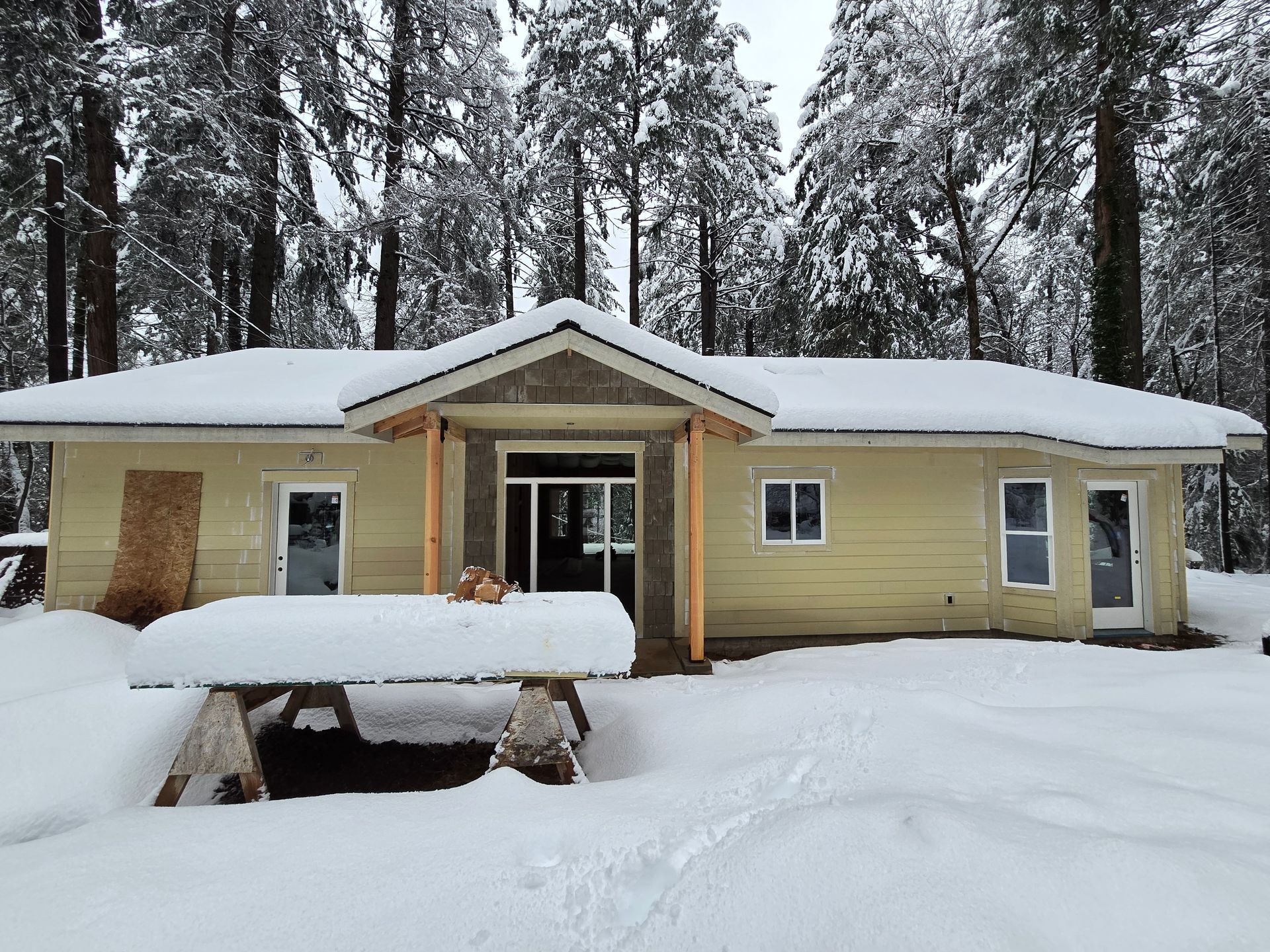 Single-story custom home surrounded by snow and forest