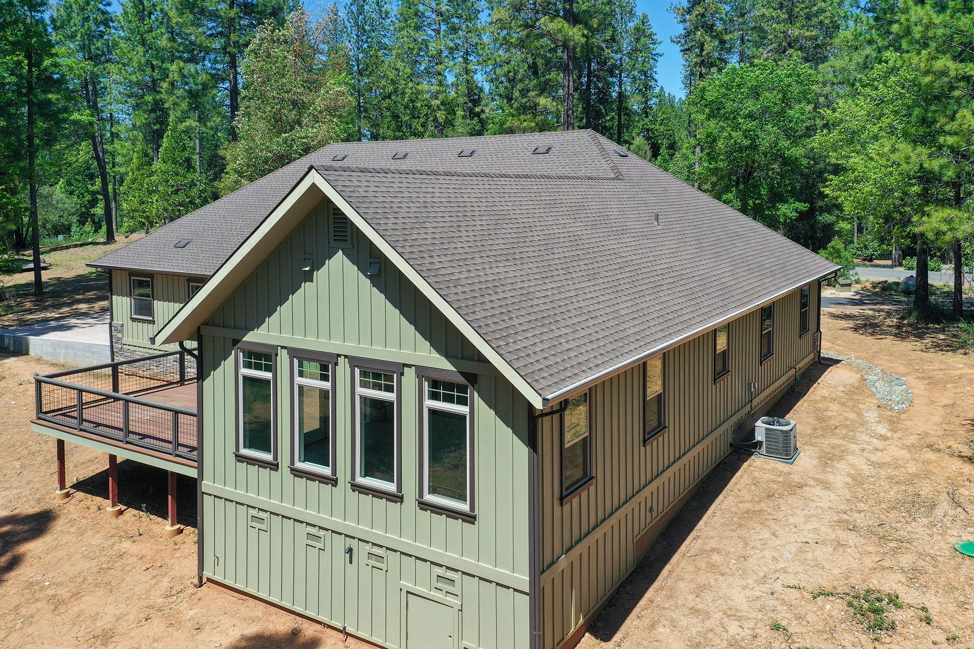 Aerial view of a home with green board and batten siding and new windows