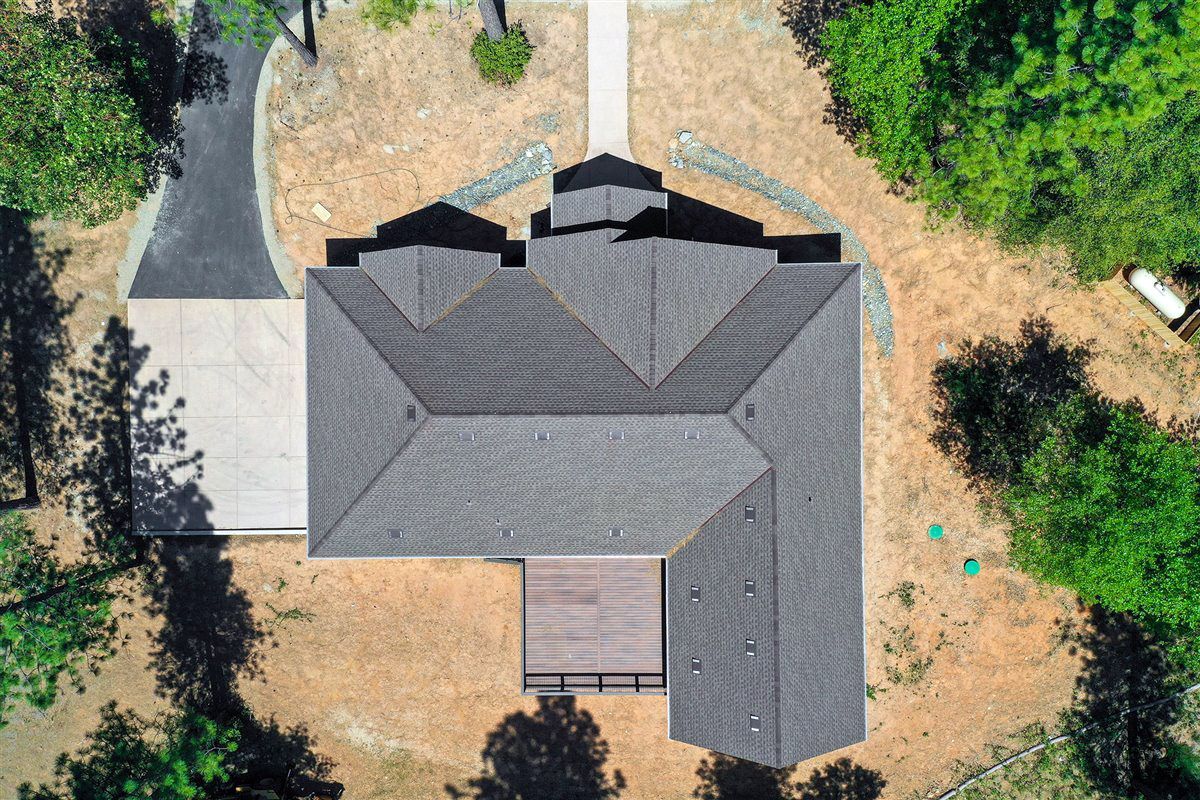 An aerial view of a house surrounded by trees and dirt.
