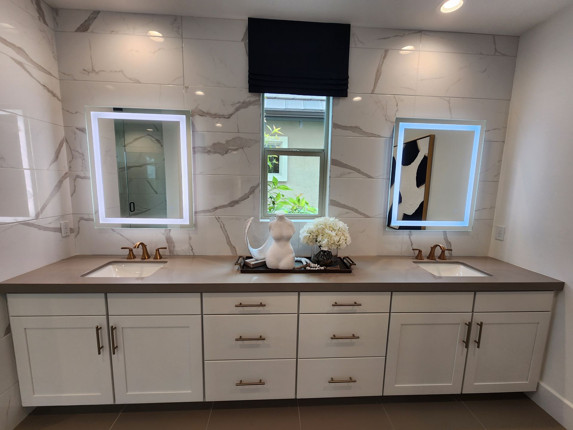 Custom bathroom remodel with a marble double vanity and LED-lit mirrors