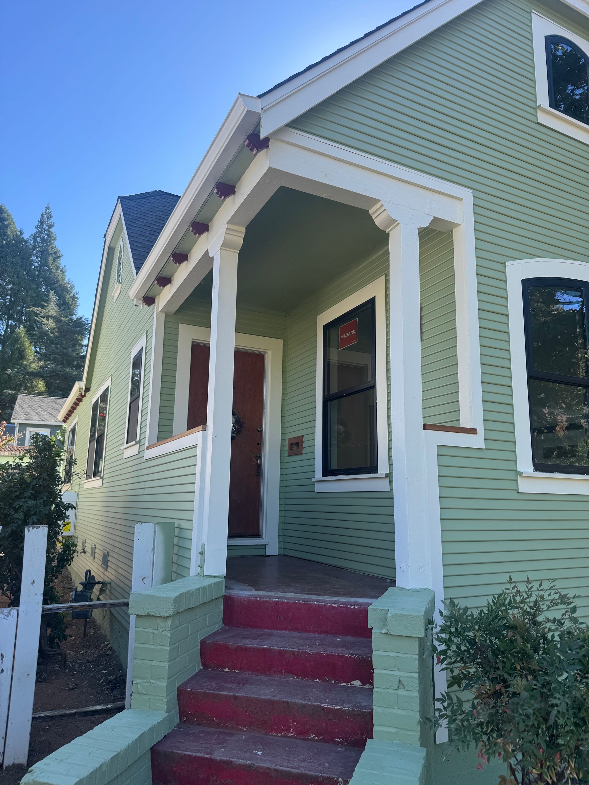 Older home with green lap siding, white trim and a covered front porch