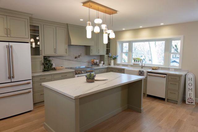 Remodeled kitchen with white cabinets, a large island and pendant lights