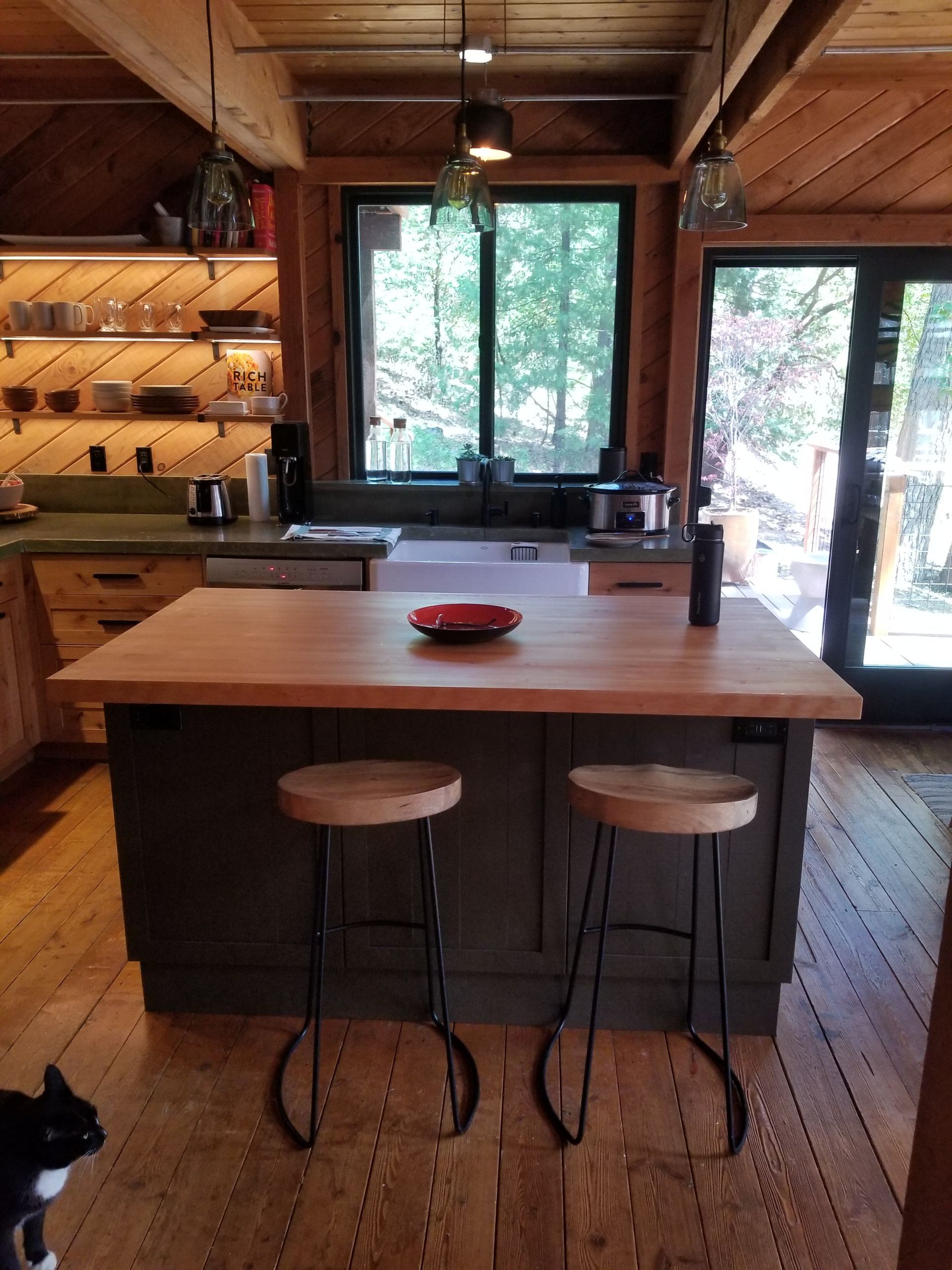 Custom kitchen with a wood-plank ceiling and a large forest-view window