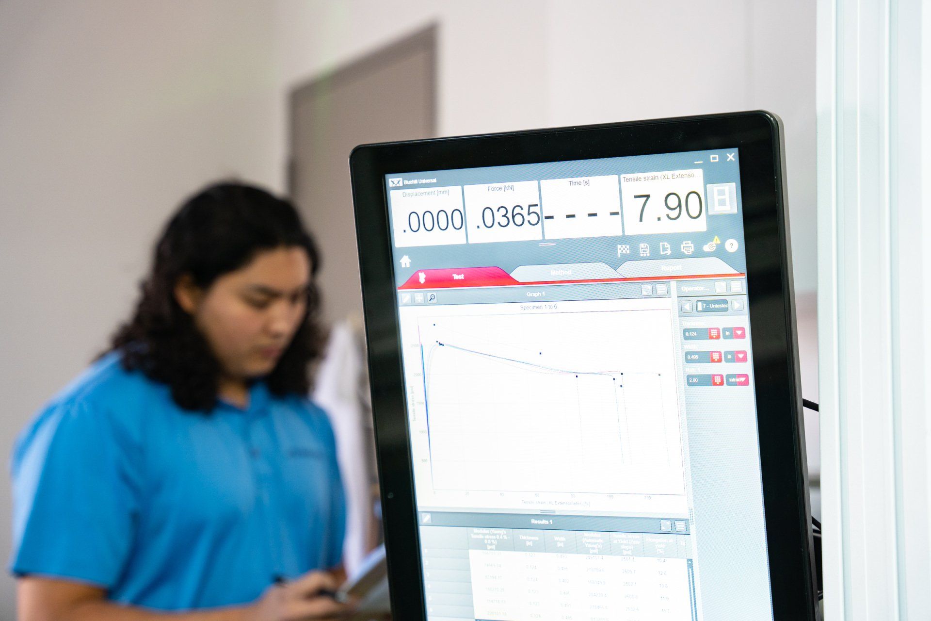 a woman in a blue shirt is standing in front of a computer monitor . a woman in a blue shirt is standing in front of a computer monitor .