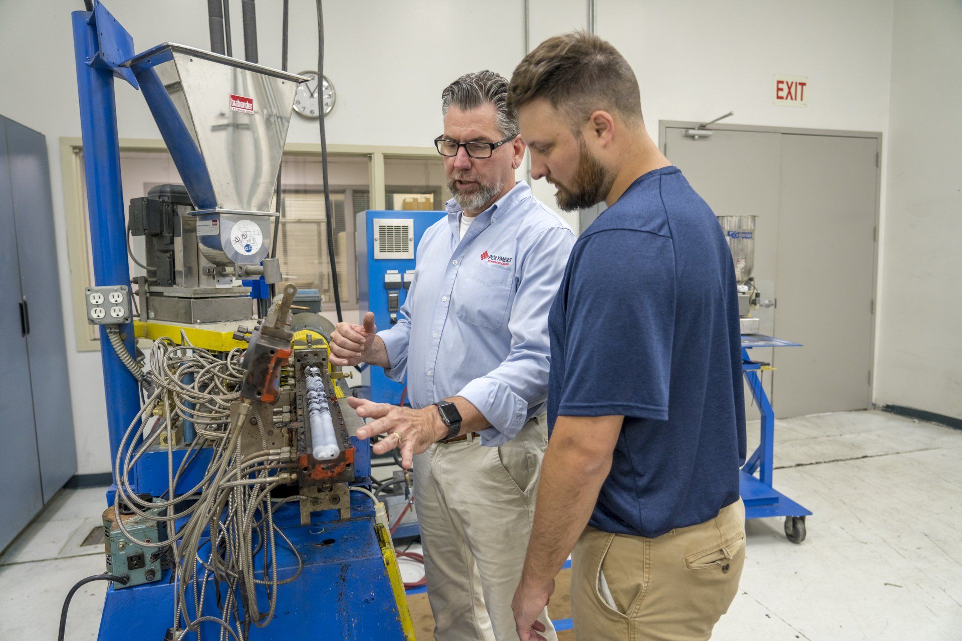 Two men are working on a machine in a factory.