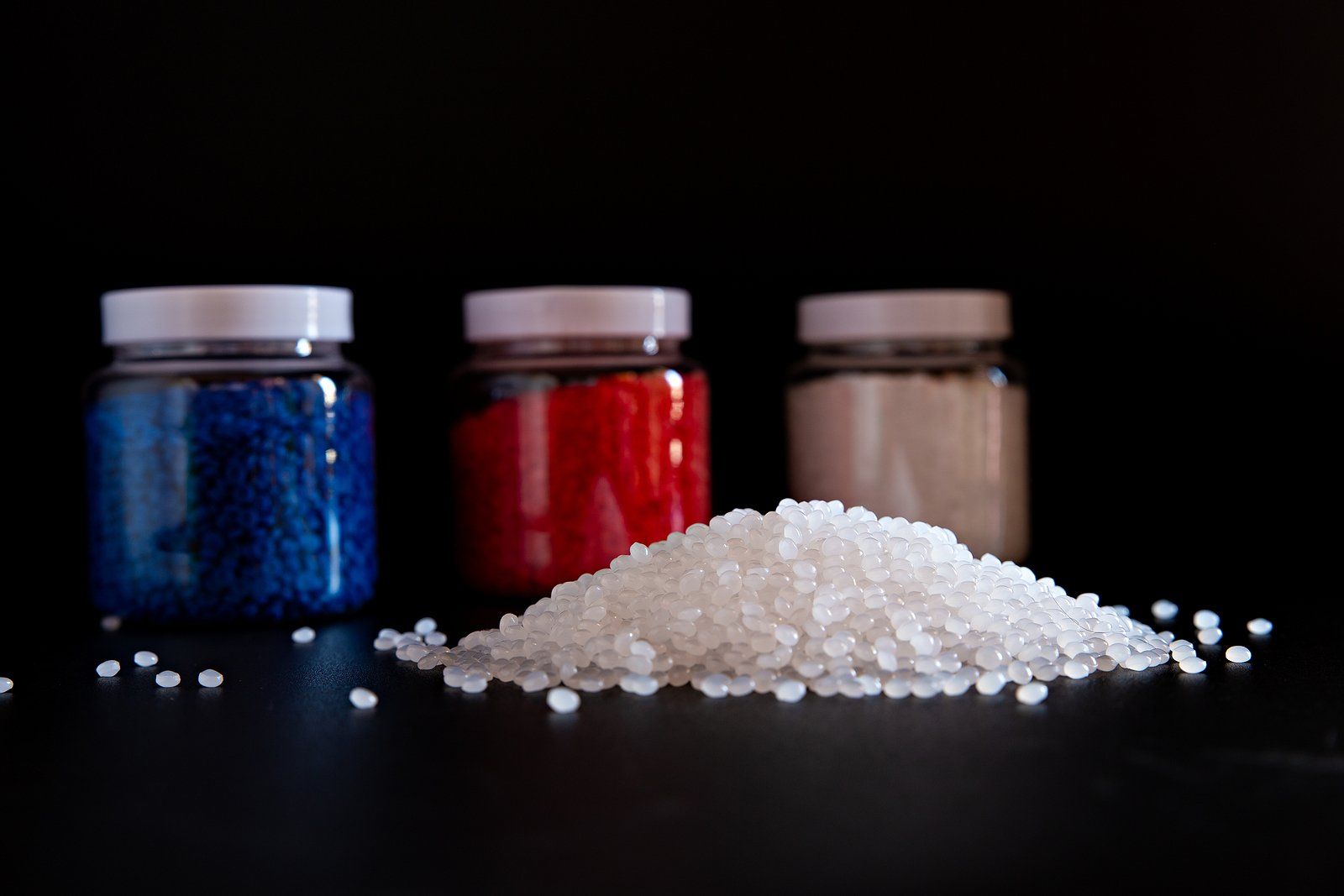 Three jars of different colored resin are sitting next to a pile of resin.