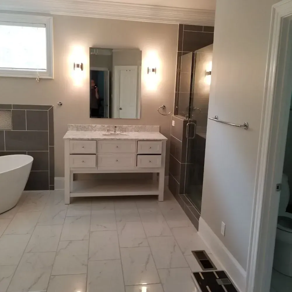 Bathroom with white vanity, large mirror, walk-in shower, and freestanding tub. Gray and white tile floors.