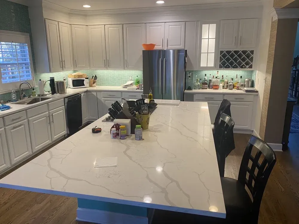 A kitchen with white cabinets, stainless steel appliances, and a large island with seating.