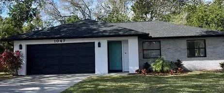 A suburban house with a black roof, garage door, and windows. The front door is teal.