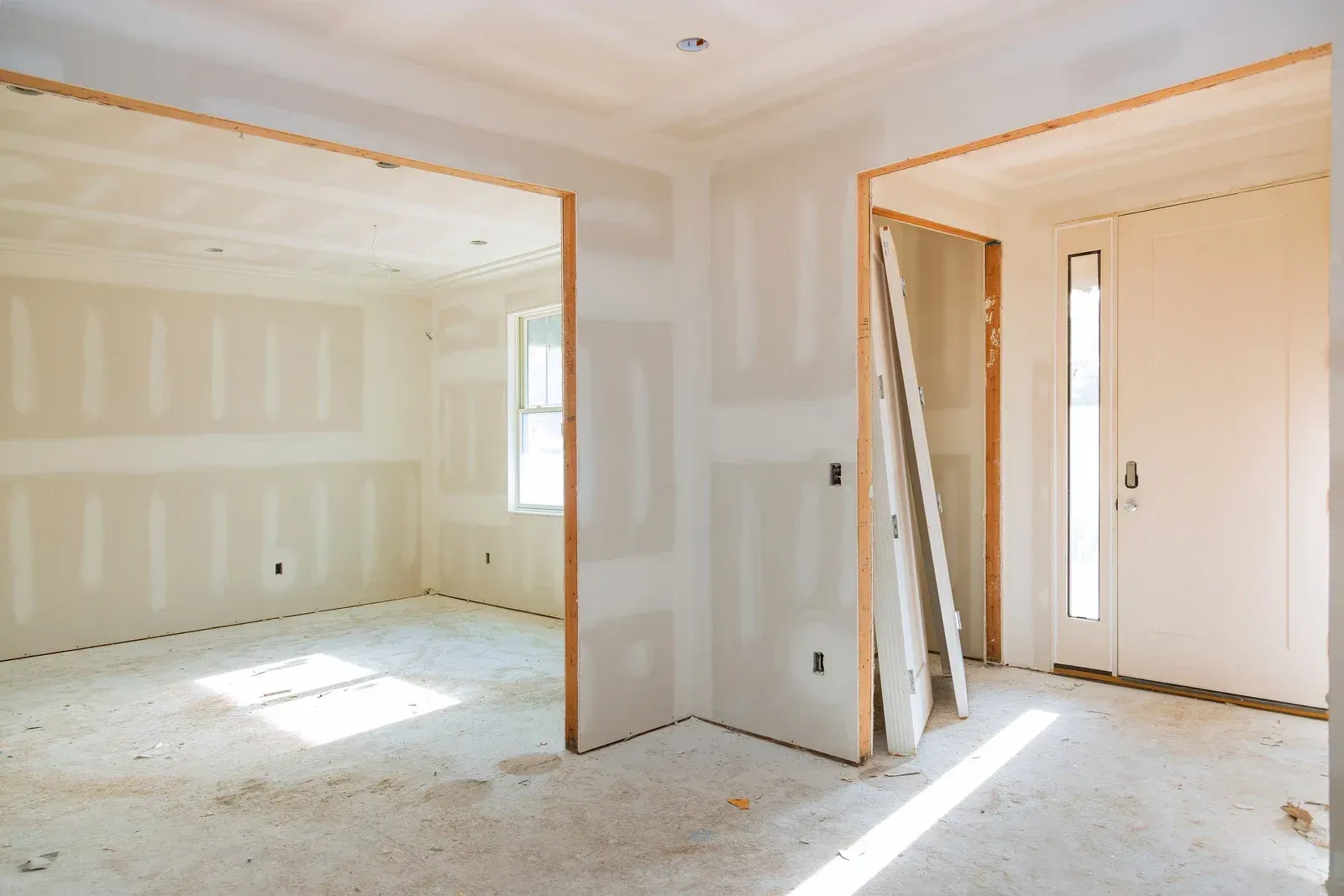Interior room under construction with drywall installed and exposed framing.