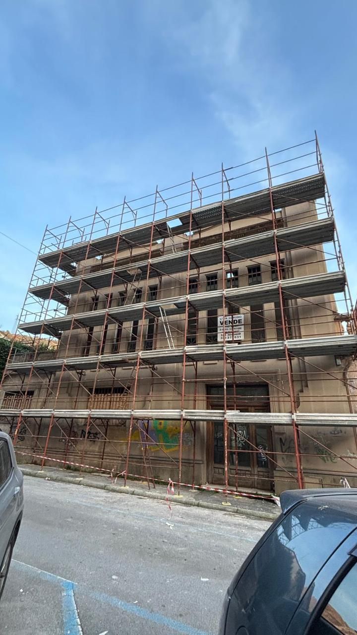 Impalcature avvolgono un edificio in mattoni a più piani in costruzione su una strada cittadina.