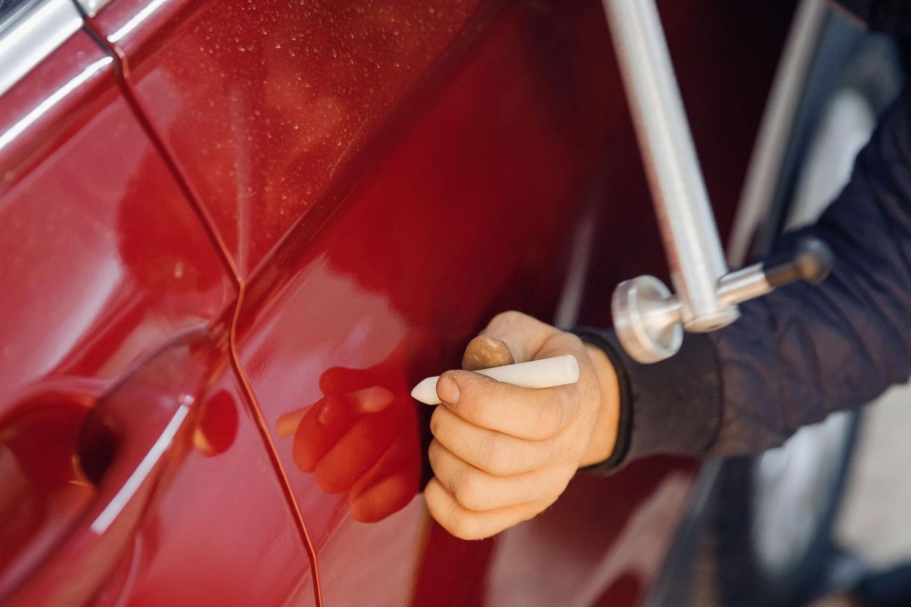 Hand polishing a red car door with a cloth
