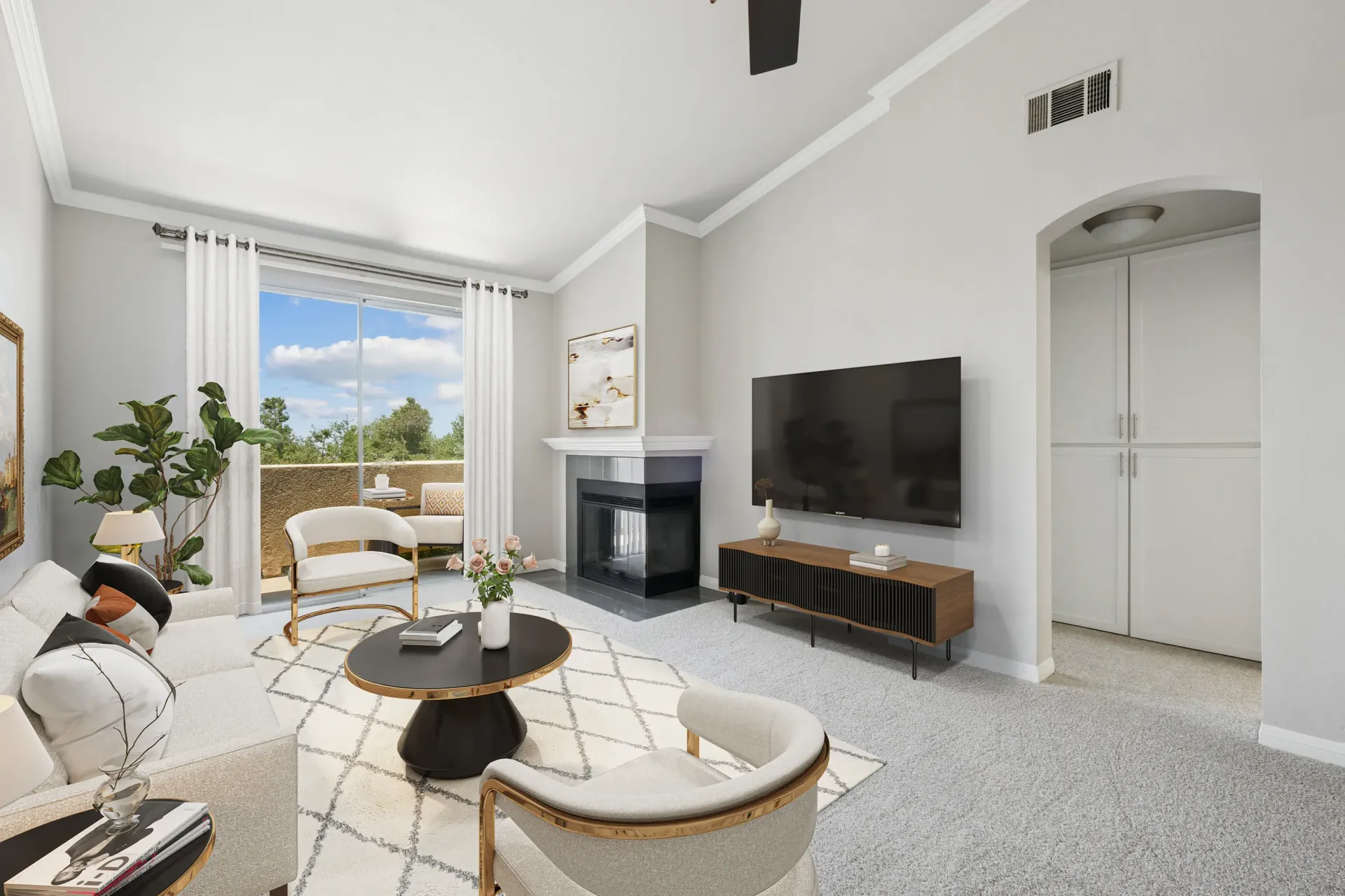 Living room interior with fireplace, TV, seating area, and a sliding glass door to the balcony.