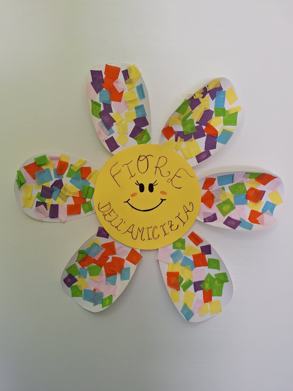 Decorazione floreale di carta multicolore con una faccina sorridente e la parola