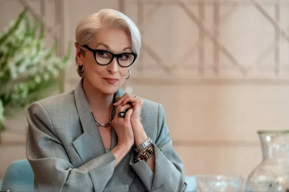 Image of Meryl Streep woman sitting in grey blazer professional at a desk with black glasses