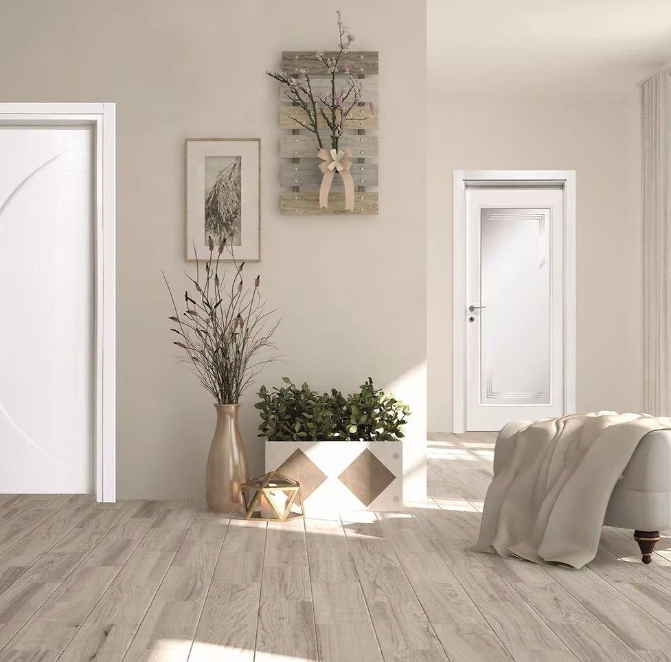 Interno con pavimento in legno, porte bianche ed elementi decorativi: vaso con rami, opere d'arte e piante.
