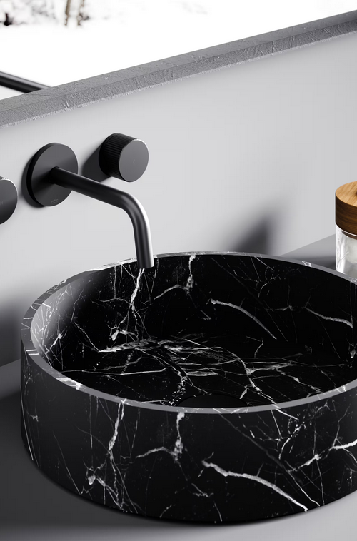 Lavandino in marmo nero con rubinetto nero opaco a parete.