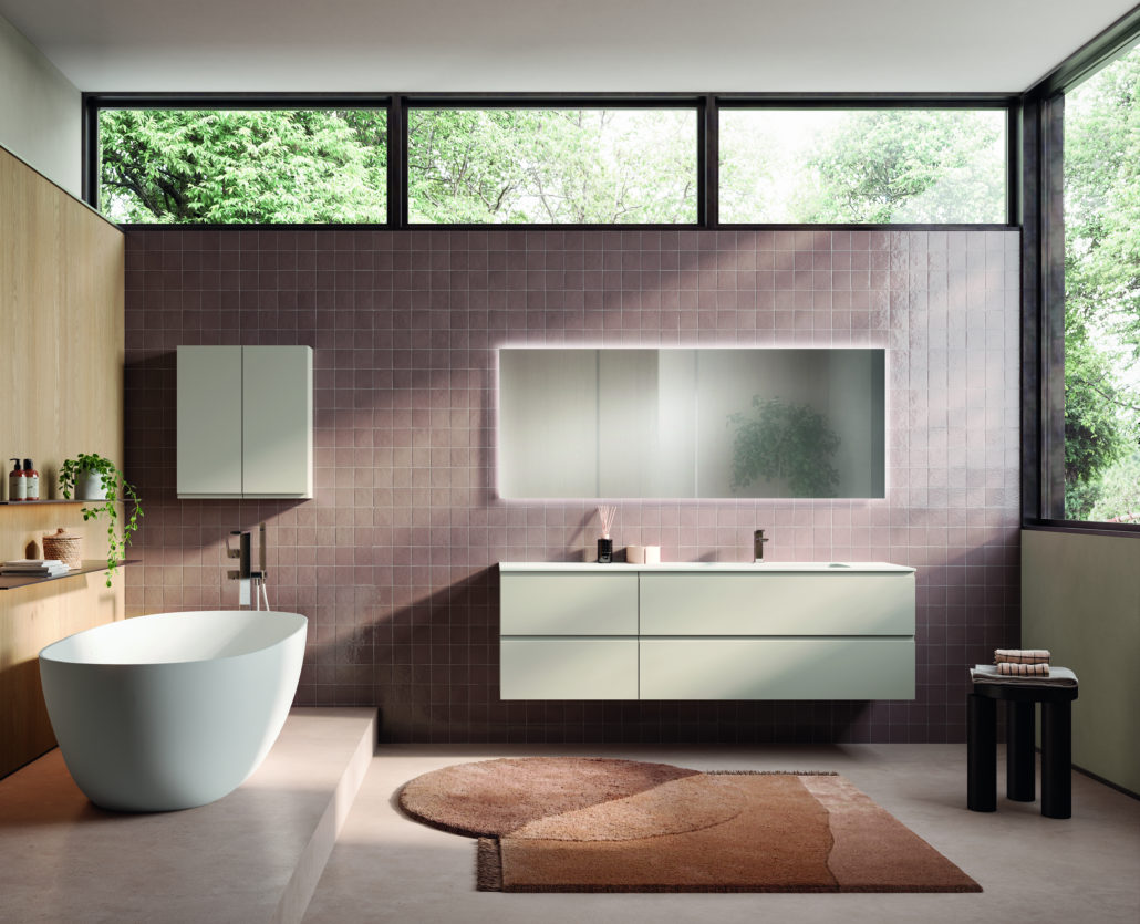 Bagno moderno con mobile lavabo verde chiaro, specchio rettangolare e vasca da bagno indipendente.