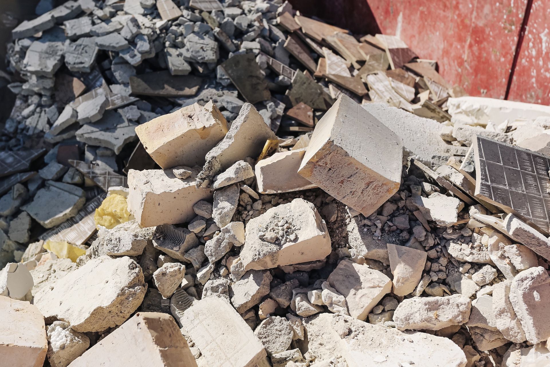 Pile of broken concrete and rubble beside a red wall