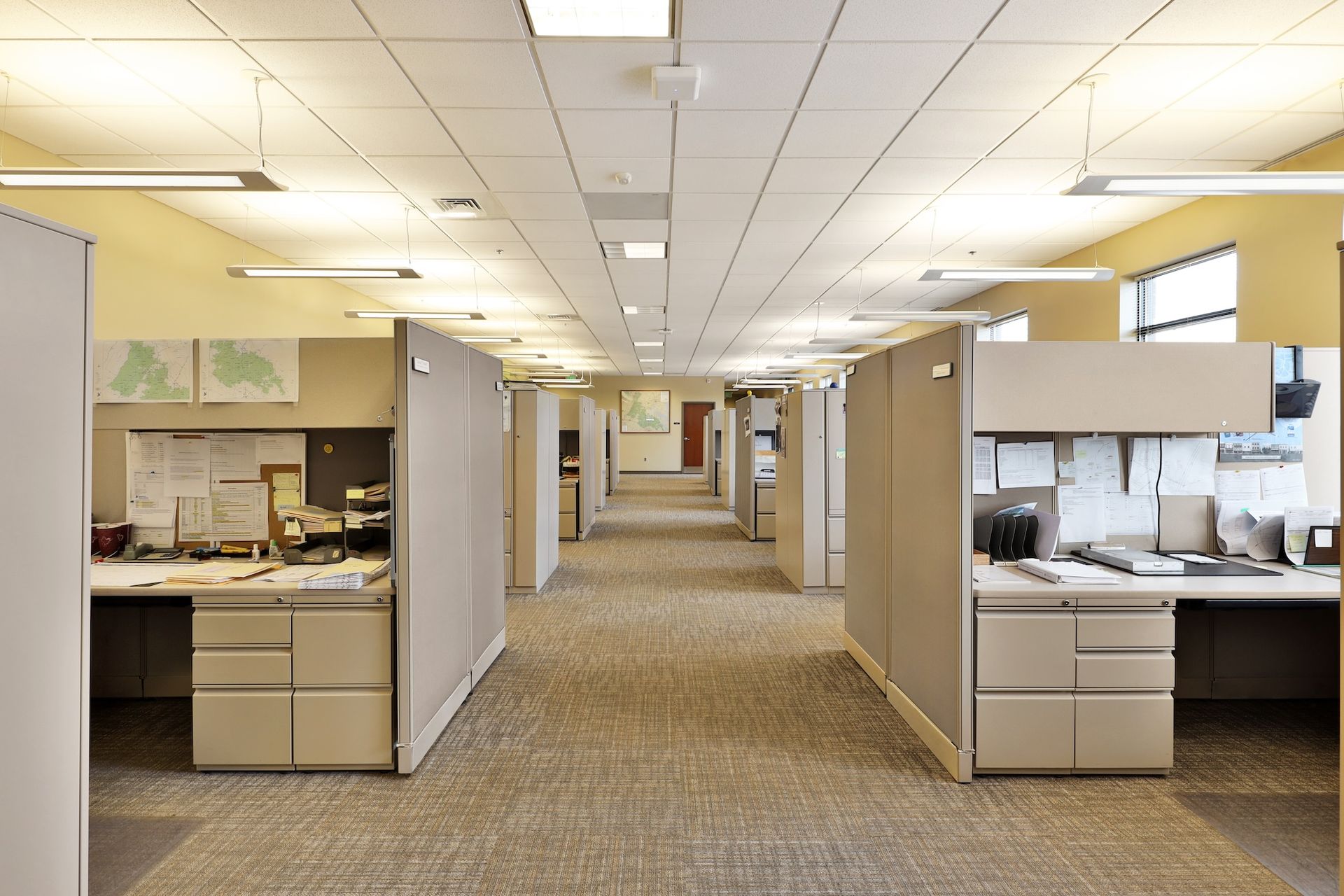 Empty office hallway with cubicles and overhead fluorescent lights