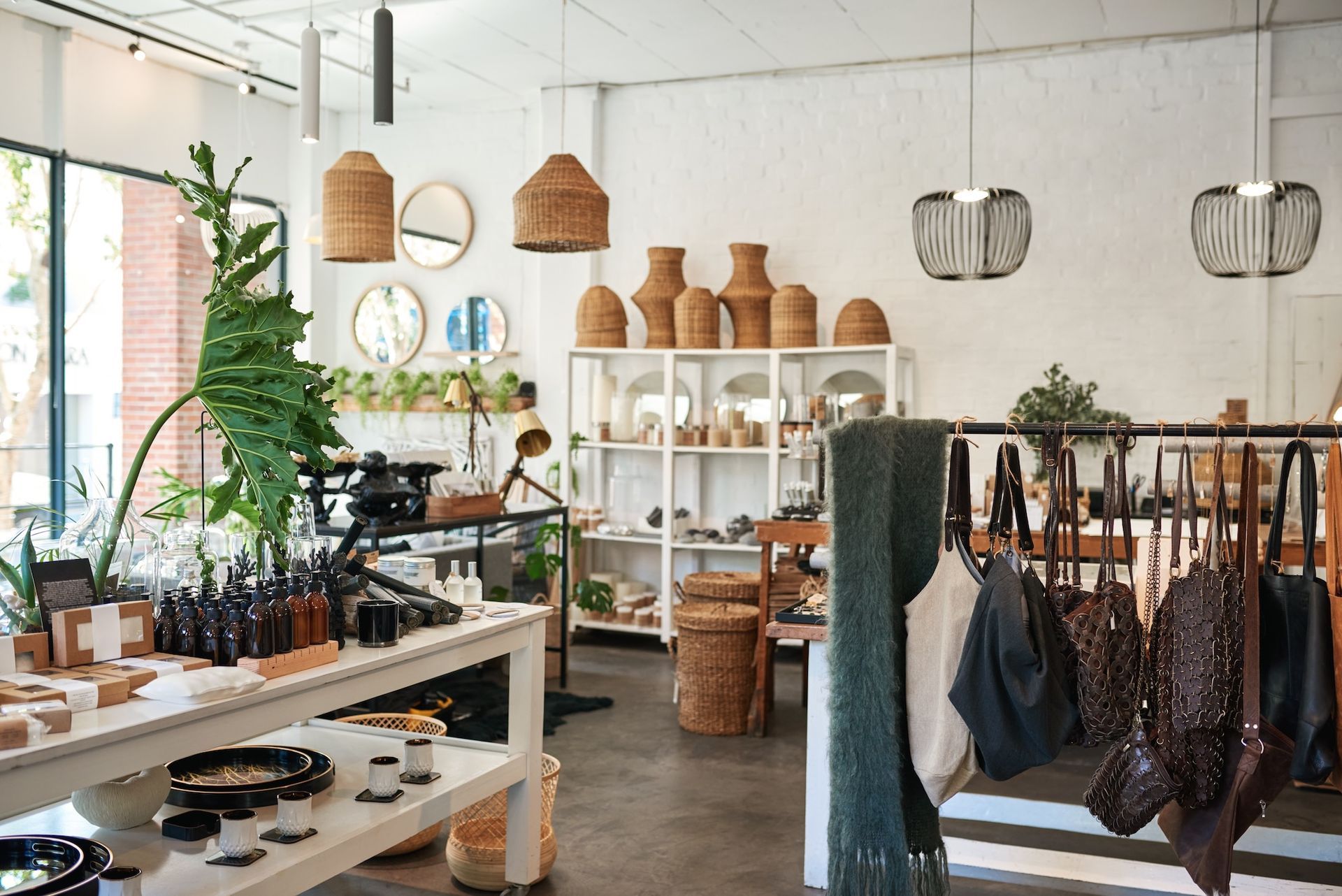 Bright boutique interior with plants, wicker lights, shelves of pottery, and a clothing rack