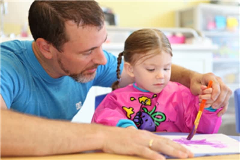 Young day care teacher teaching his student
