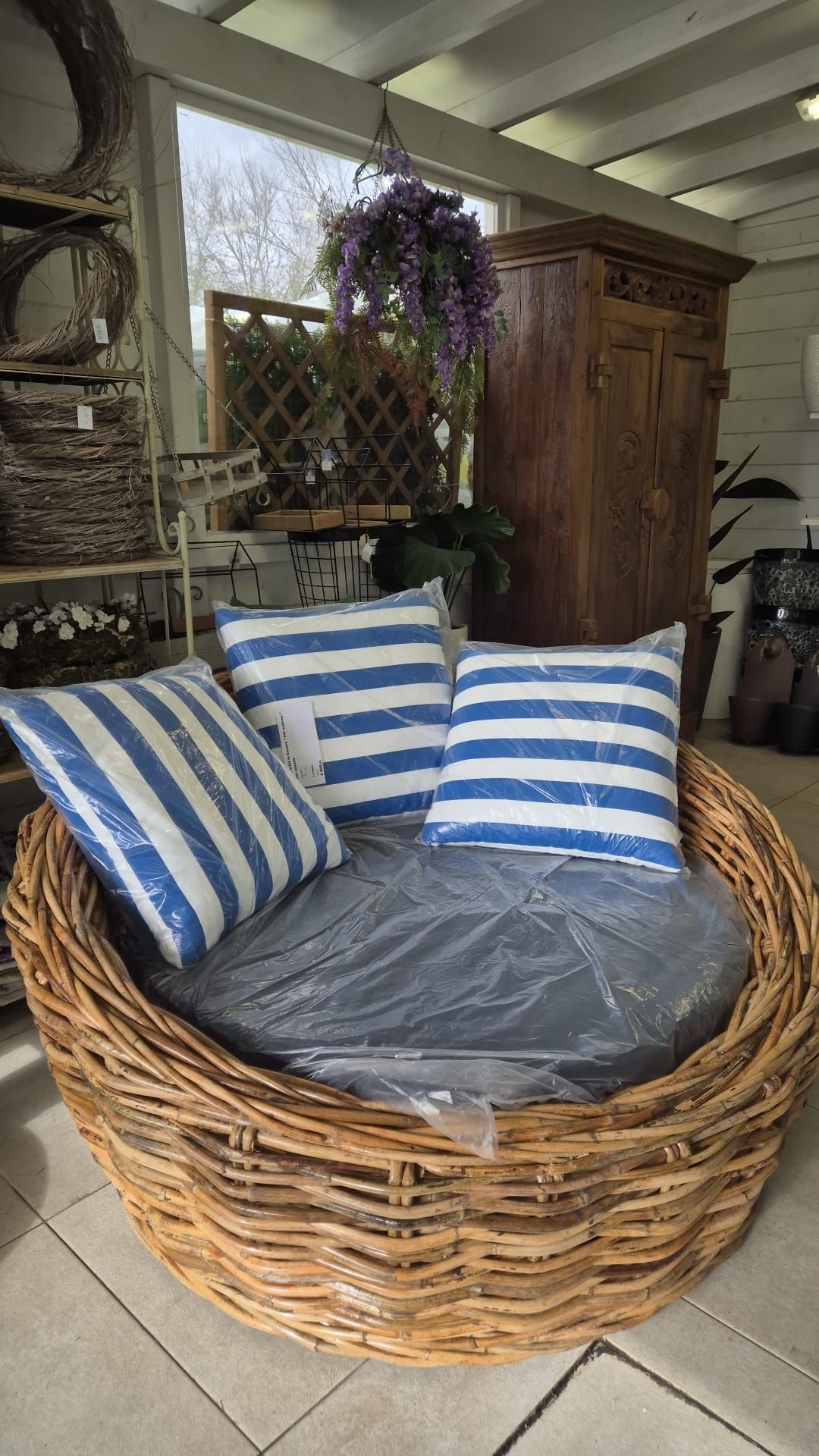 Divano letto in vimini con cuscini a righe bianche e blu in una veranda.