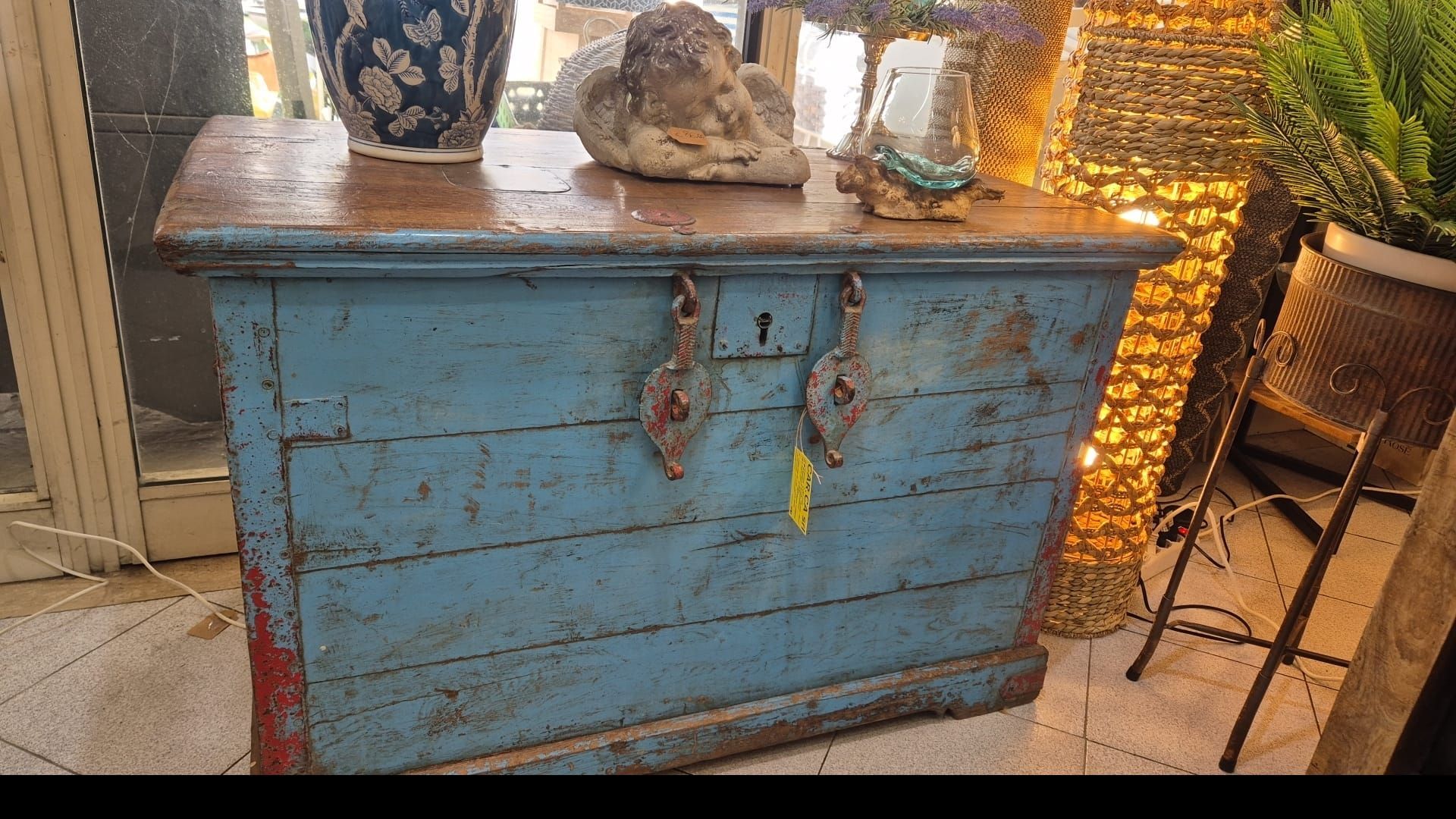 Cassapanca in legno blu con chiusure in metallo, esposta in un negozio.