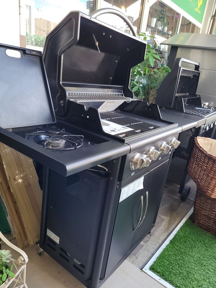 Barbecue a gas nero con fornello laterale, coperchio aperto, griglie in acciaio inox e manopole di controllo.