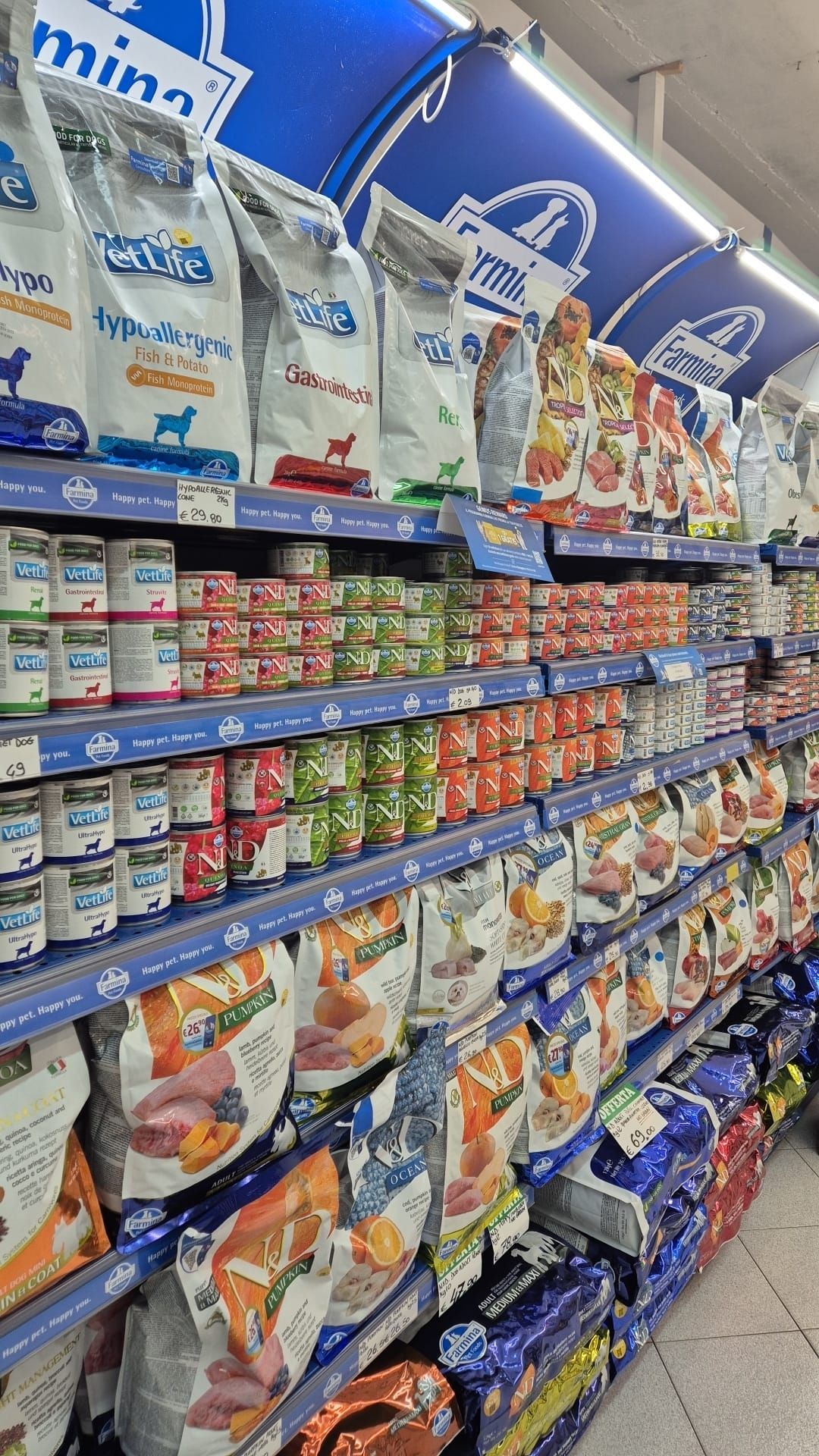 Scaffali pieni di vari prodotti alimentari per animali domestici in un negozio.