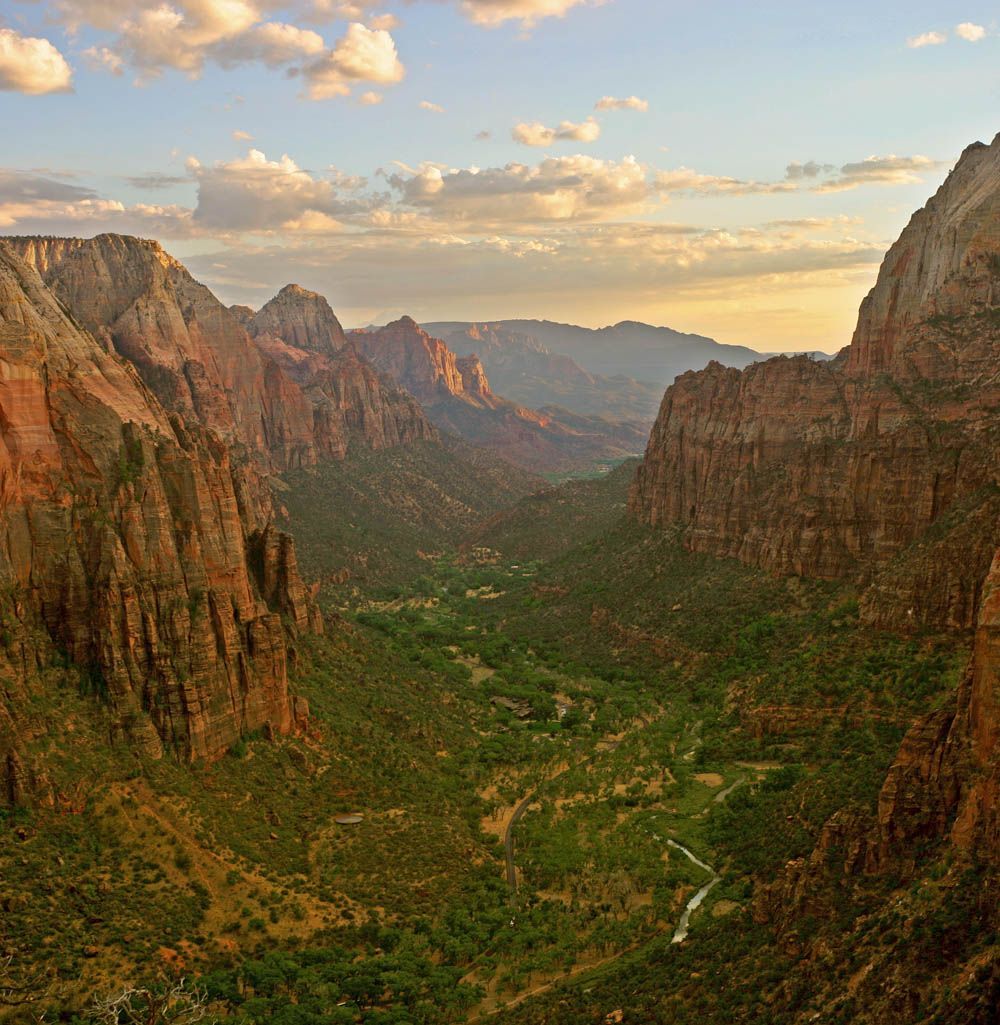 Zion Canyon from Angels Landing at sunset Canyon valley at sunset with red cliffs, green floor, and a winding river under a cloudy sky