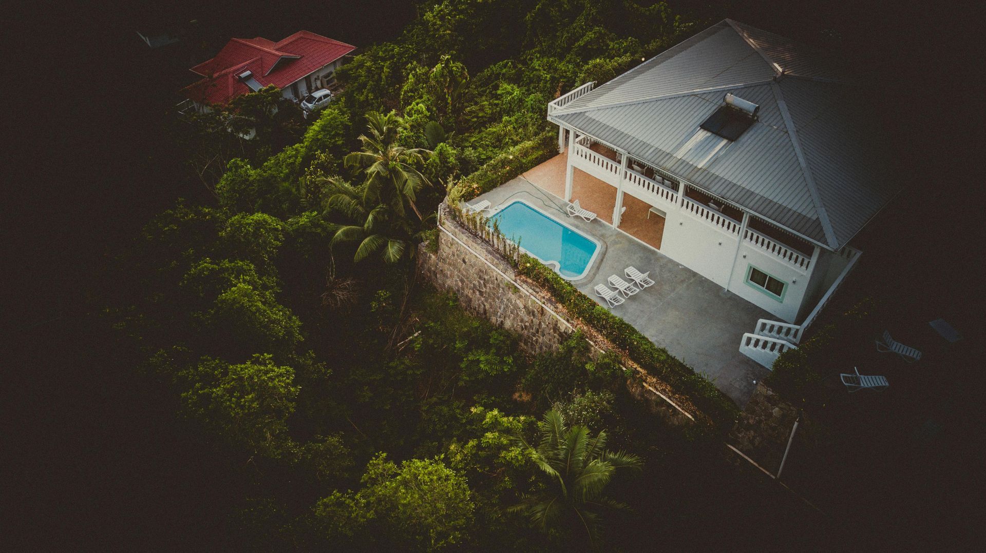 House with pool nestled in lush green hillside.