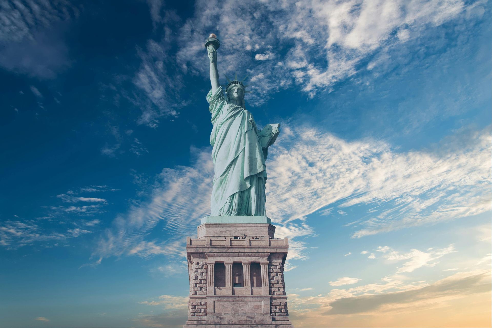 Statue of Liberty against a blue sky with fluffy white clouds.